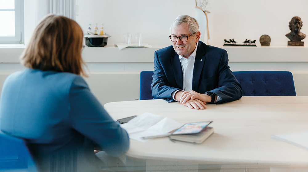 Dr. Jürgen Ude sitzt mit Lisa Baaske an einem Tisch in seinem Büro für ein Interview (c) Hannah Theile Uni Magdeburg