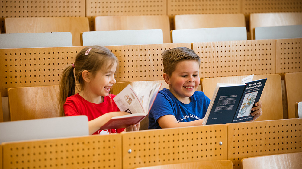 /unimagdeburg_media/Presse/Bilder/Pressemitteilungen/2024/Die+Kinder_Uni_Botschafter+Nora+und+Henri+sitzen+im+H%C3%B6rsaal+mit+B%C3%BCchern+in+der+Hand+%28c%29+Jana+D%C3%BCnnhaupt+Uni+Magdeburg-height-560-width-1000-p-115912.jpg