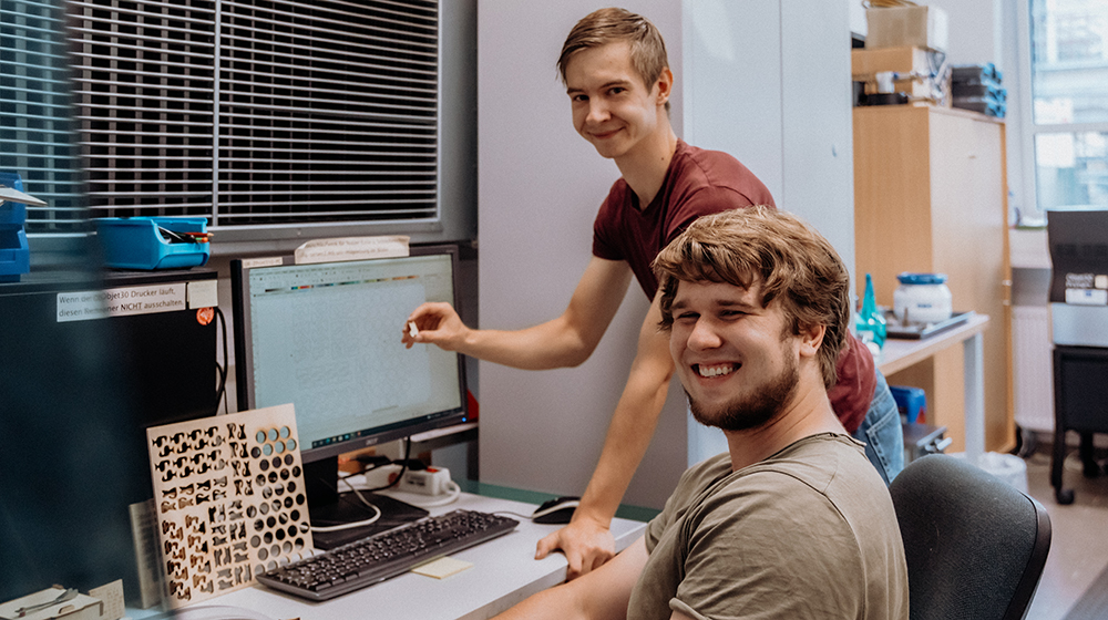 Jakob Emmerling (hinten) und Benjamin Steiger (vorne) haben im FabLab der Uni Magdeburg ein eignenes Gesellschaftsspiel entwickelt (Foto: Hannah Theile / Uni Magdeburg)